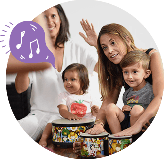 Caregivers and young children playing hand drums together in a Zumbini promotional photo.